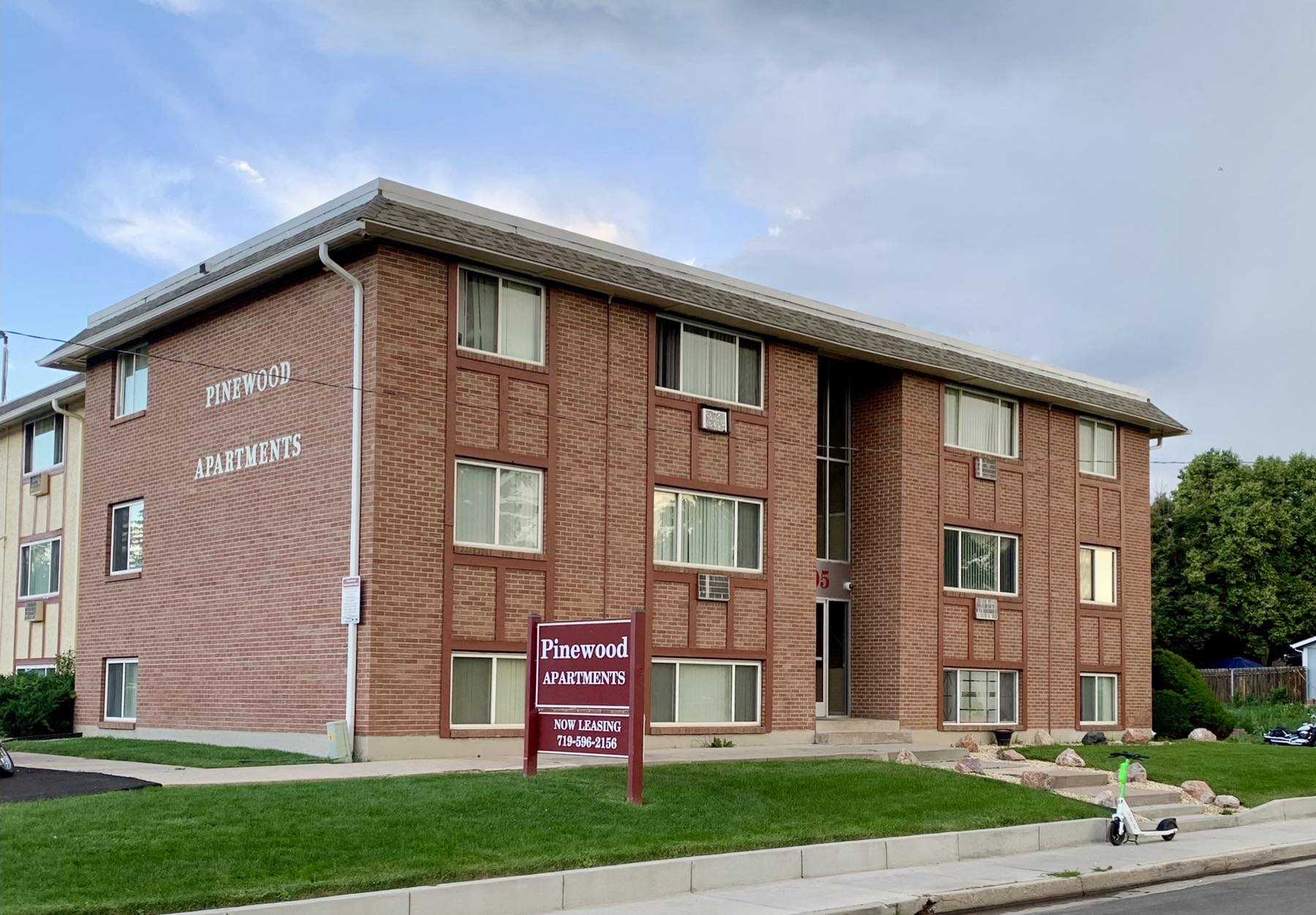 Pinewood Apartments seen from East Dale Street, with the property sign reading Now Leasing
