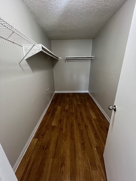 Walk-in closet with hanging rods, wire shelving and wood-look flooring