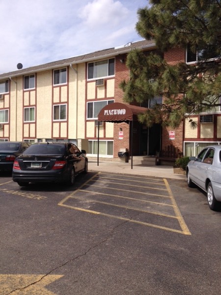 Covered Pinewood entryway with parking in the foreground