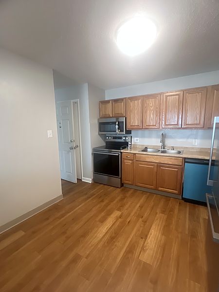 Kitchen with oak cabinets, stainless steel range, overhead microwave and dishwasher beside a wide open floor area
