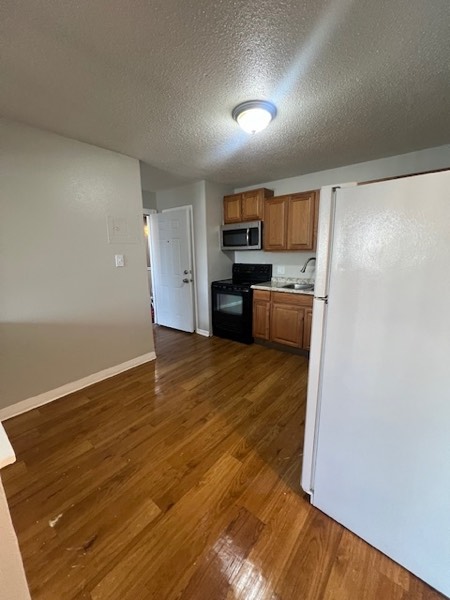 Kitchen opening onto a living area with wood-look plank flooring