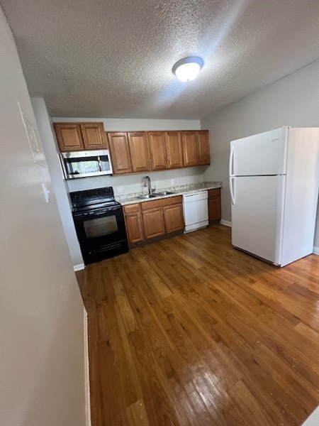 Kitchen with wood cabinets, overhead microwave, dishwasher and full-size refrigerator