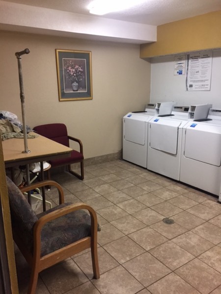 Laundry room with washers, dryers, a table and seating